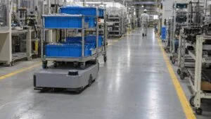 部品箱を載せた台車を運ぶ自律走行搬送ロボットと工場の通路