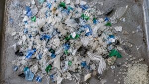 粉砕された色とりどりの廃プラスチック片と再生樹脂ペレット