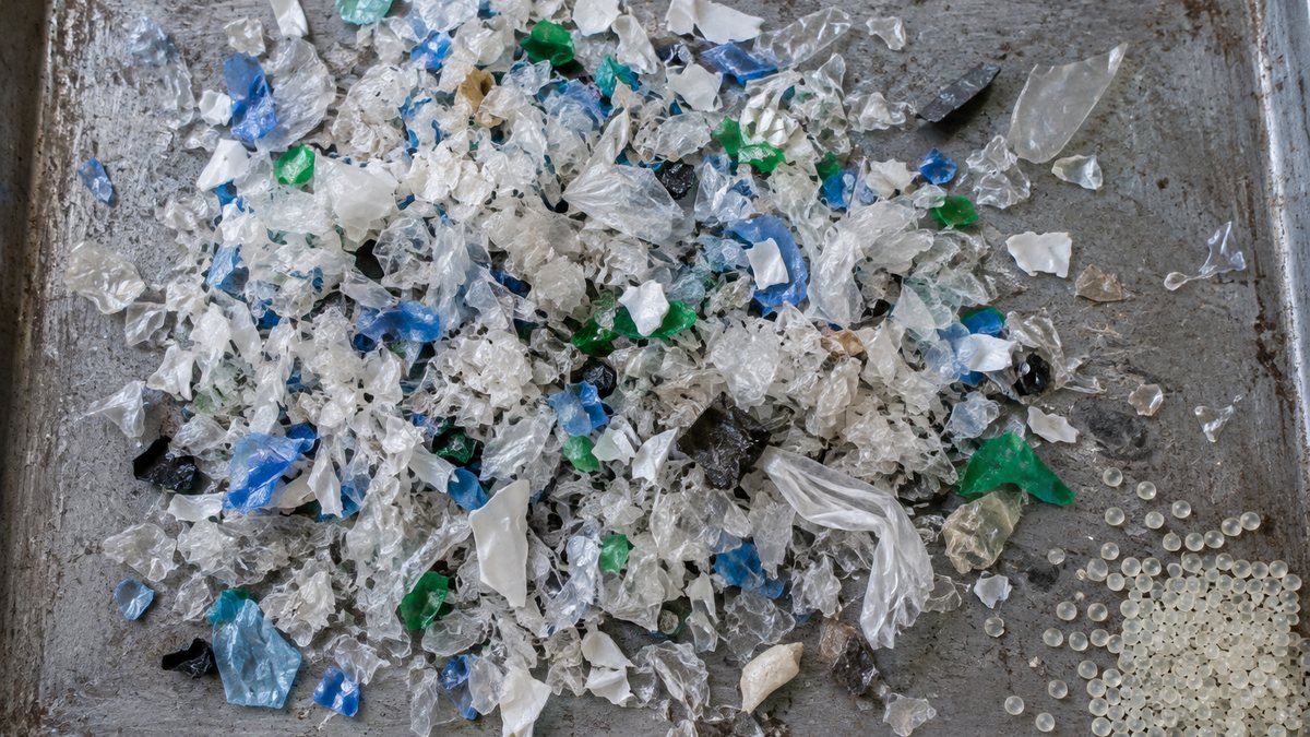 粉砕された色とりどりの廃プラスチック片と再生樹脂ペレット