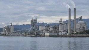 湾の対岸から見たセメント工場の煙突とサイロ