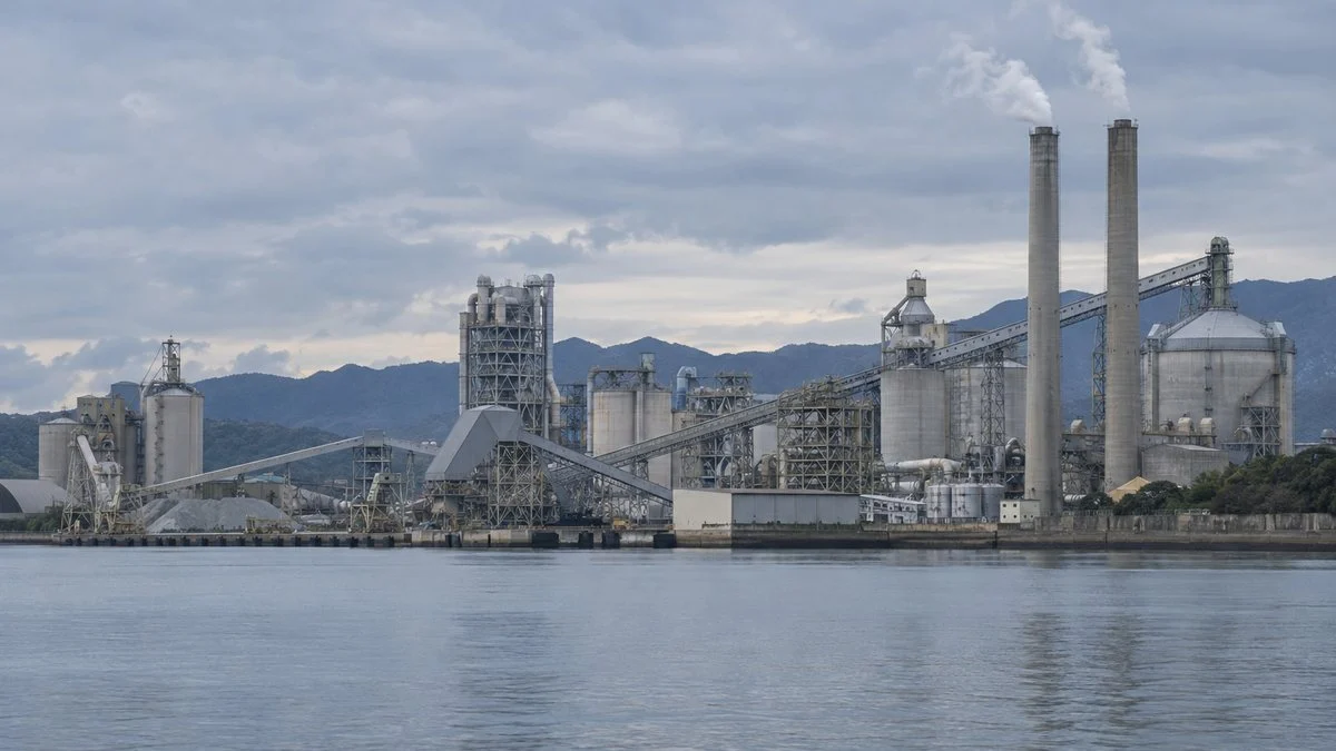 湾の対岸から見たセメント工場の煙突とサイロ