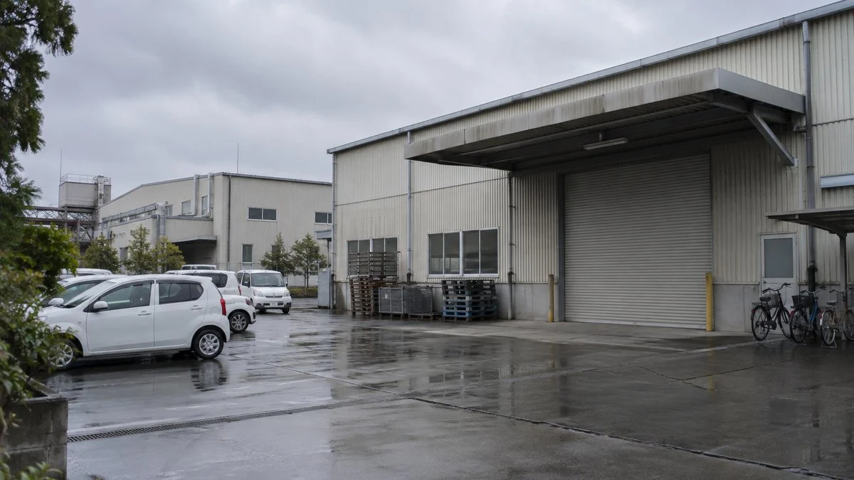 Exterior of a mid-sized factory with a loading dock and employee parking