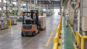 歩行通路と走行レーンが柵で分けられた工場内を走るフォークリフト