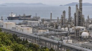 高台から見た臨海コンビナートの化学工場群と配管ラック、岸壁のタンカー