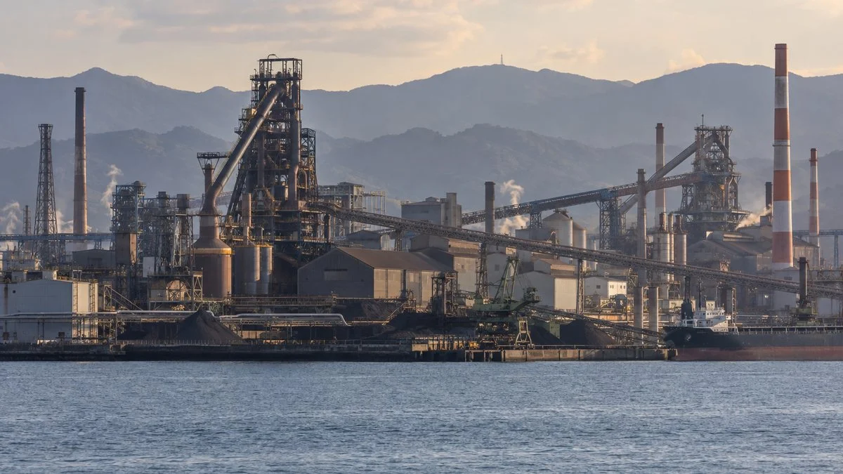 海の対岸から見た臨海部の製鉄所の高炉とベルトコンベヤ