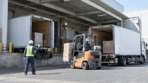 工場の出荷バースに接車した大型トラックとパレットを運ぶフォークリフト