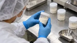 白い菌末のサンプル容器を手袋をした手で確認する様子